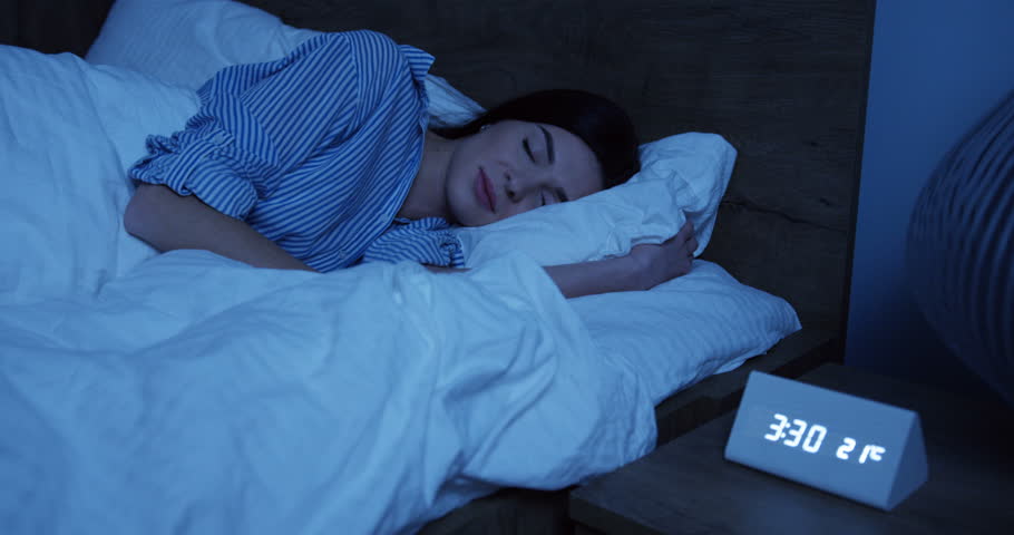 Young pretty woman in pajama sleeping in her bed late at night near the electronical watch. Indoors Royalty-Free Stock Footage #1100063645