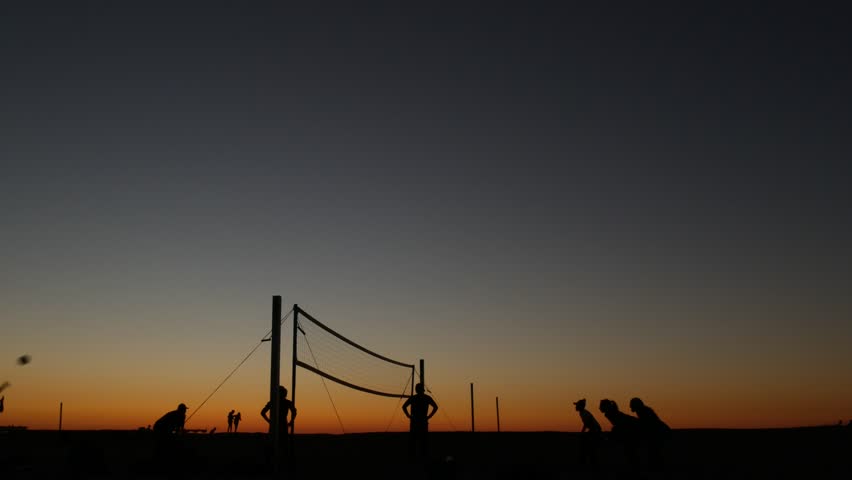 Volleyball net silhouette on beach sport court at sunset, people playing on California coast, USA. Sport field for volley ball game players by ocean shore. Twilight sky of Mission beach, San Diego.
