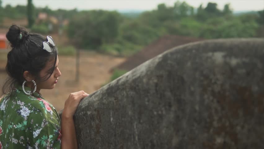 Dreamy girl looking into a distance over a concrete wall. Focused look. House in a background.