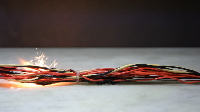 Electrical wiring and wires are highlighted on a dark background. A short circuit in the twisted wires from the computer. Flames, sparks and smoke. Royalty-Free Stock Footage #1100071965