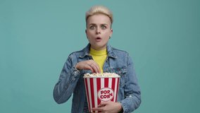 Stylish lady watching a horror movie. Close-up shot of caucasian woman eating fresh, delicious popcorn in the cinema. High quality 4k footage