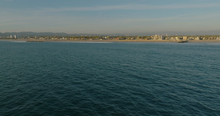 Above the ocean (Venice beach). Venice Beach Skate Park with the Ocean View Palm Trees in Los Angeles California Pacific Coast Line. Aerial shot moving along the coast of Venice Beach, CA at sunset. 