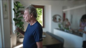 A contemplative senior man standing at home living room while drinking coffee. Mature older person staring out window - Powered by Shutterstock - Get 15% off with code: PIKWIZARD15