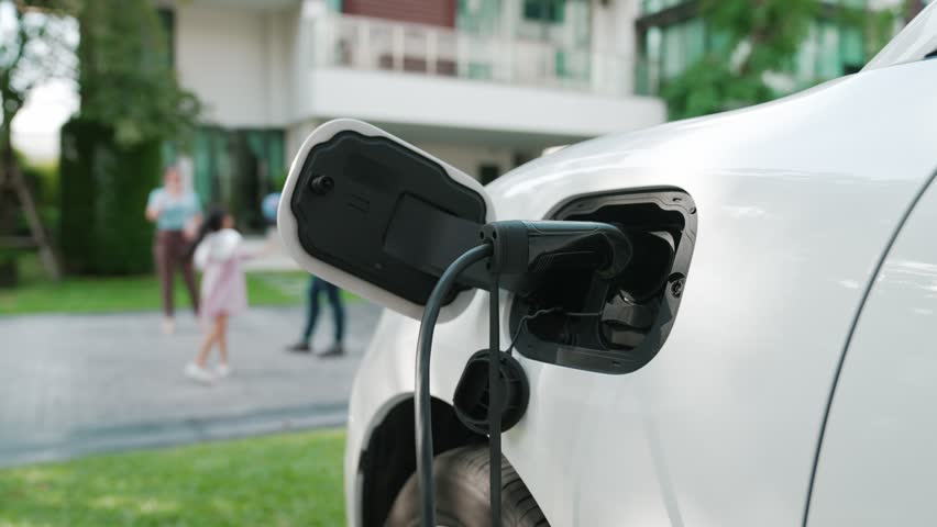 Progressive parent have returned from picking up daughter at school with concept of electric vehicle and renewable energy, charging station for EV car at home. Alternative eco transportation. Royalty-Free Stock Footage #1100085791