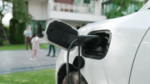 Progressive parent have returned from picking up daughter at school with concept of electric vehicle and renewable energy, charging station for EV car at home. Alternative eco transportation. 스톡 비디오