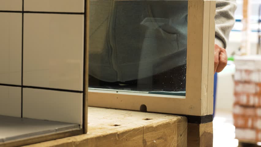 Man scoops glue off wood