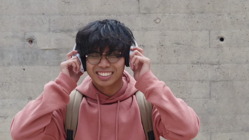 Young boy with headphones listening to music laughing. Music application, millennial youth