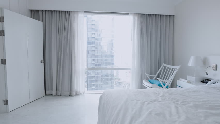 Woman checking in at luxury hotel, walks to her window, city view. Female travelling in city hotel looks at view 