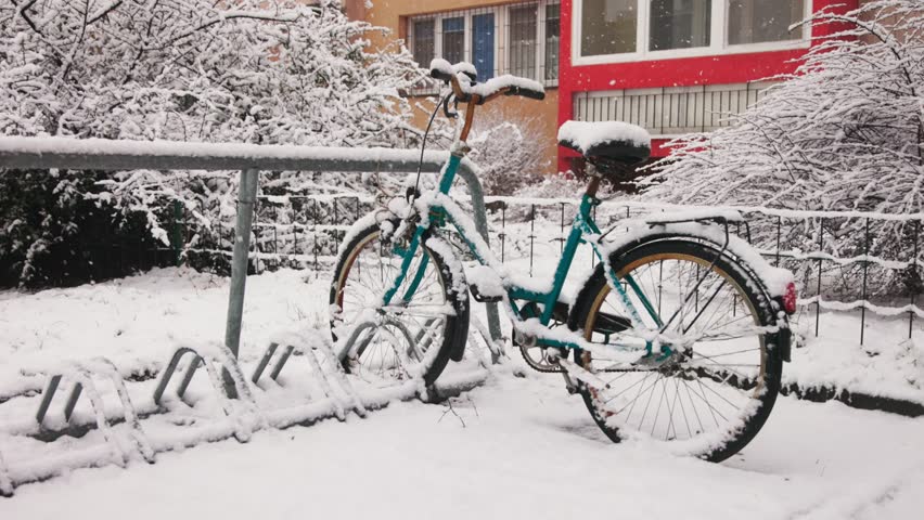Blue bicycle near the building under falling snow in Krakow, Poland. Slow motion video.