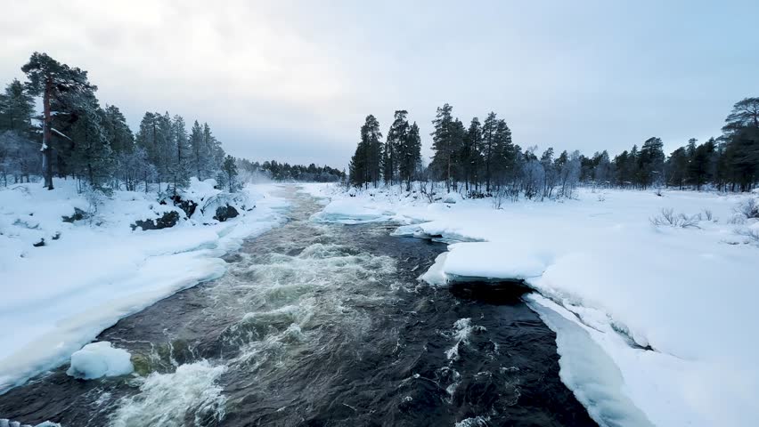 Shot of Inari areas in Finland in winter. Uutua suspension bridge. Jäniskoski and the snowy path. The partially frozen river. Trekking Northern Finland near Inari typical village of Sami culture.