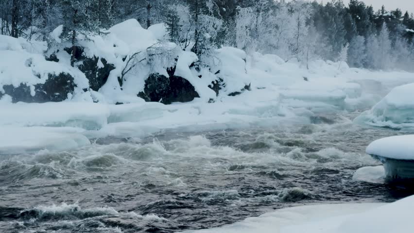 Shot of Inari areas in Finland in winter. Uutua suspension bridge. Jäniskoski and the snowy path. The partially frozen river. Trekking Northern Finland near Inari typical village of Sami culture.