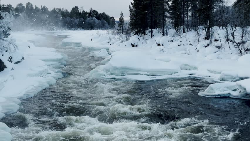 Shot of Inari areas in Finland in winter. Uutua suspension bridge. Jäniskoski and the snowy path. The partially frozen river. Trekking Northern Finland near Inari typical village of Sami culture.