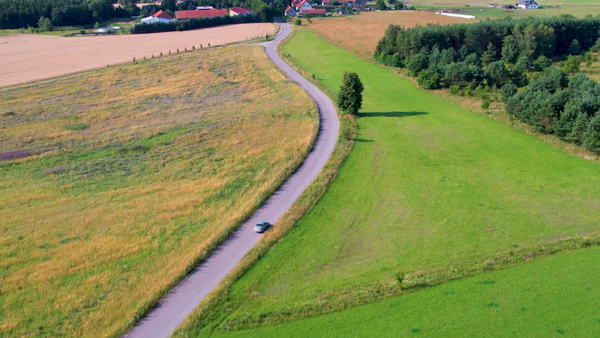 Road Trip Travel Journey Vacation in Europe Nature Countryside Rural Landscape. Aerial View Car Moving on Countryside Road Between Trees and Agriculture Fields. Houses Village in Countryside Poland.