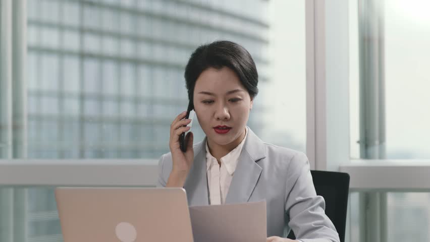 Young asian business woman working in office using laptop computer and cellphone | Shutterstock HD Video #1100110265