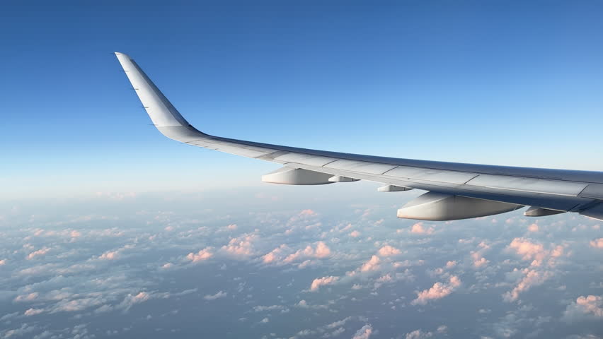 Airplane flight. Wing of airplane flying above clouds with sunset sky. Illuminator view on plane wing. Traveling by air on Airplane or Aircraft. 4K video shot on smartphone. Airplane Window View USA