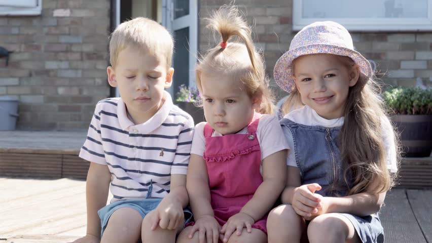 Three cute little Children enjoys delicious ice cream cone. Child eating watermelon popsicle. Kids Siblings snack sweets in Home Garden. Summer holiday Hot weather Sunny Day. Childhood, Food Candy