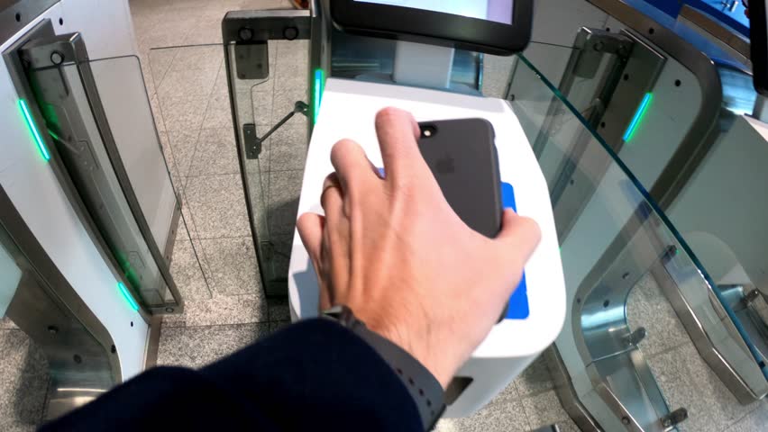 Eindhoven, Netherlands, January 30, 2022: POV SHOT - Man passing through the turnstiles at Eindhoven Airport Terminal, using his smart phone as pass. Automated ticket checking machine.