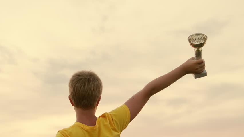 Boy, Healthy lifestyle. Child is winner, champion since childhood. Child athlete celebrates his victory, joyfully raises his hands with cup and jumps joyfully. Concept of childrens sports victories. | Shutterstock HD Video #1100122439