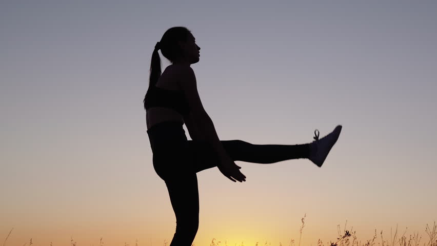 Workout and warm-up in fresh air. Girl is engaged in gymnastics. Athlete exercising in nature. Young woman goes in for sports in park at sunset. Healthy girl is engaged in fitness, outside city in sun | Shutterstock HD Video #1100122733
