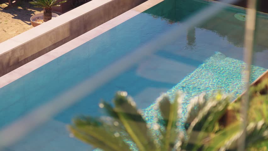Slow revealing shot of a private pool with abstract ripples on the surface  Royalty-Free Stock Footage #1100124919