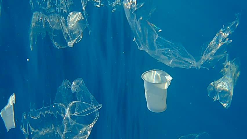 VERTICAL VIDEO, Close-up of a lot of the transparent plastic debris slowly drifs under surface of blue water in sunrays. Plastics garbage floats underwater. Plastic pollution of Ocean. Slow Motion | Shutterstock HD Video #1100130323