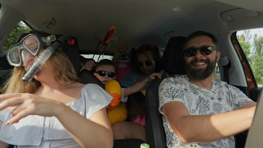 A crazy funny family with children traveling in a car. Woman in diving mask with a snorkel, everyone is having fun and dancing, enjoying their vacation, freedom Royalty-Free Stock Footage #1100130339