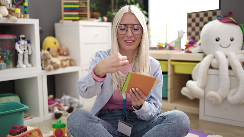 Young blonde woman preschool teacher having vocabulary lesson at kindergarten Royalty-Free Stock Footage #1100136837