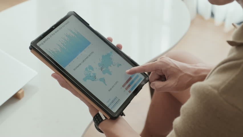 Hand of young male analyst scrolling through graphic financial data in tablet and studying charts illustrating market changes and development of new stock corporations | Shutterstock HD Video #1100139675