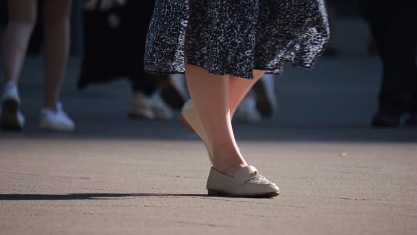 Legs of a crowd of people walking down the street, close-up of people's feet. Slow motion. Many feet walk on the pavement. Low view of crowded people walking in the square. Urban crowd. Royalty-Free Stock Footage #1100142639