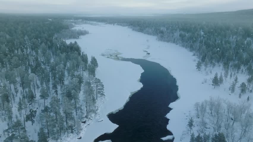 Shot of Inari areas in Finland in winter. Uutua suspension bridge. Jäniskoski and the snowy path. The partially frozen river. Trekking Northern Finland near Inari typical village of Sami culture.