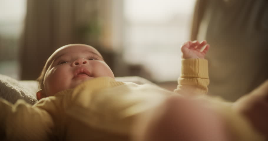 Portrait of a Cute Asian Baby Resting in a Crib, Surrounded by a Soft Blanket. Active Baby Waking Up Under the Warm Morning Sunlight, Looking Around, Cooing and Interacting with his Surroundings | Shutterstock HD Video #1100144317