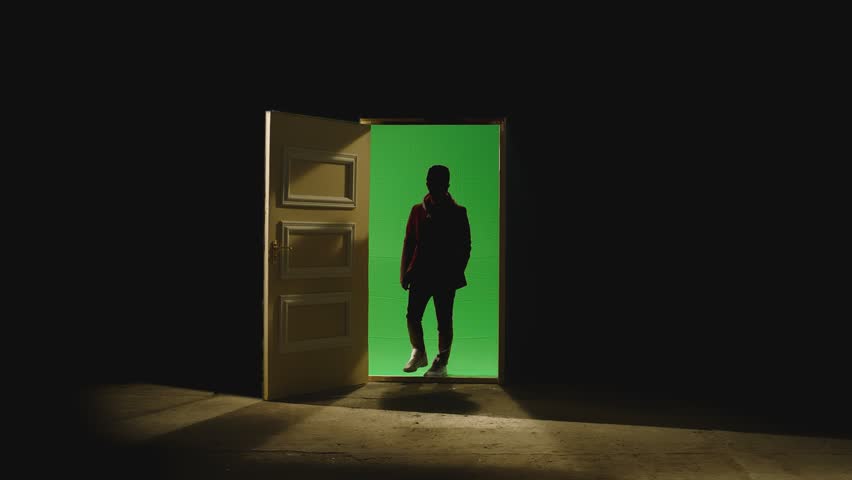 Front view of a man walking in front of an open door with darkness behind . Footage of businessman walking on floor near door with green screen. Concept of way out of the situation