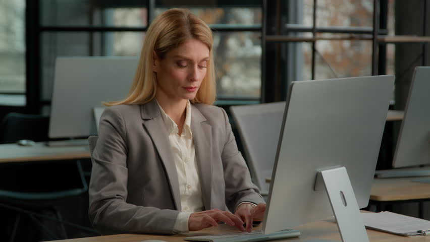Adult businesswoman middle-aged manager dance sitting at office desk after success computer win. Female woman specialist work online in creative company dancing celebrate successful e-commerce project Royalty-Free Stock Footage #1100145181