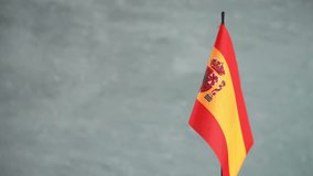 State flag of Kingdom of Spain waving on gray background. Spanish flag and place for text
