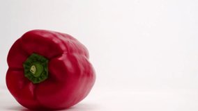 Whole, bright red bell pepper vegetables falling onto white table top and bouncing into each other before settling close up in slow motion - Powered by Shutterstock - Get 15% off with code: PIKWIZARD15