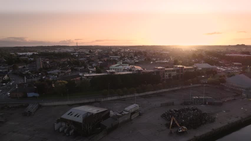 Slow drone pull back from Dundalk harbor while the sun sets over the city. Dundalk, Ireland.