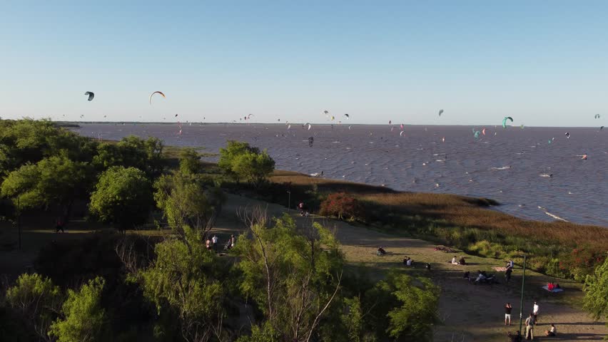 Aerial Orbit shot of many Kitesurfer on River with trees on coastline in Vicente Lopez Area in Buenos Aires Royalty-Free Stock Footage #1100152119