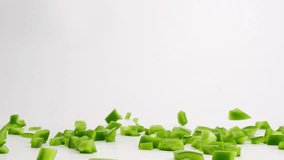 Cubed green bell pepper pieces falling onto white table top and bouncing into a pile in slow motion - Powered by Shutterstock - Get 15% off with code: PIKWIZARD15