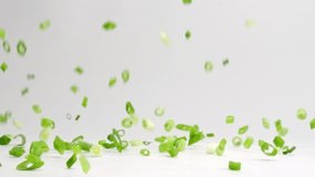 Diced and chopped green onion pieces falling and bouncing onto white table top in slow motion - Powered by Shutterstock - Get 15% off with code: PIKWIZARD15