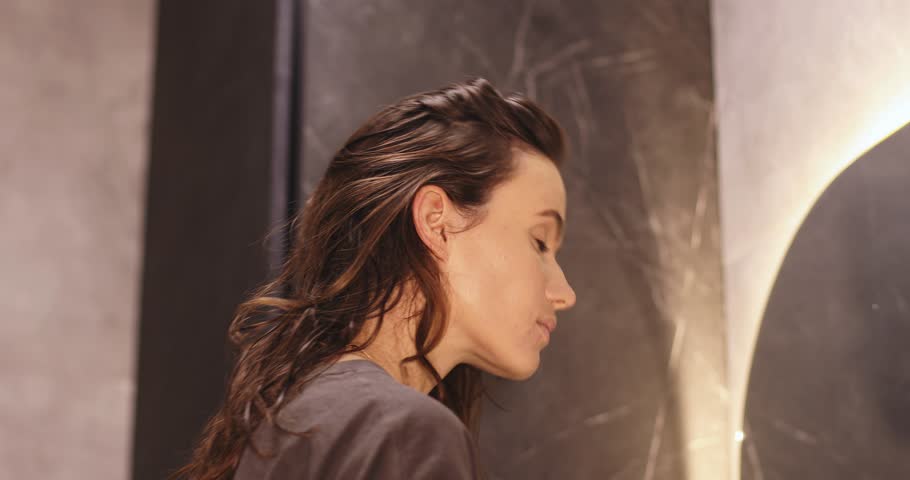 Close up happy young woman smile and looking in mirror doing skin care applying make up brush on her cheek and beauty treatment at home,Wellness girl self care with beauty product at home.