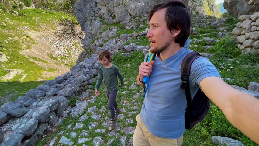 A young family is walking among abandones ancient buildings close to the castle over the city of Kotor in Montenegro. An ancient rocky road leads to the top of the mountain. Slowmotion video