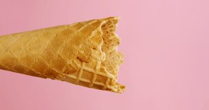 Vertical video, Vanilla ice cream scoop in cone on pink background, delicious ice cream concept.