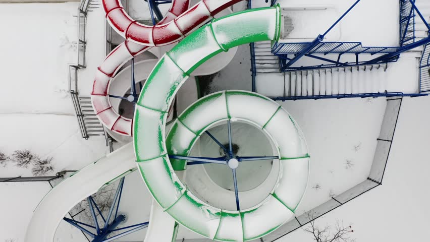 Aerial top down, snow covered empty water slides at a pool during winter season