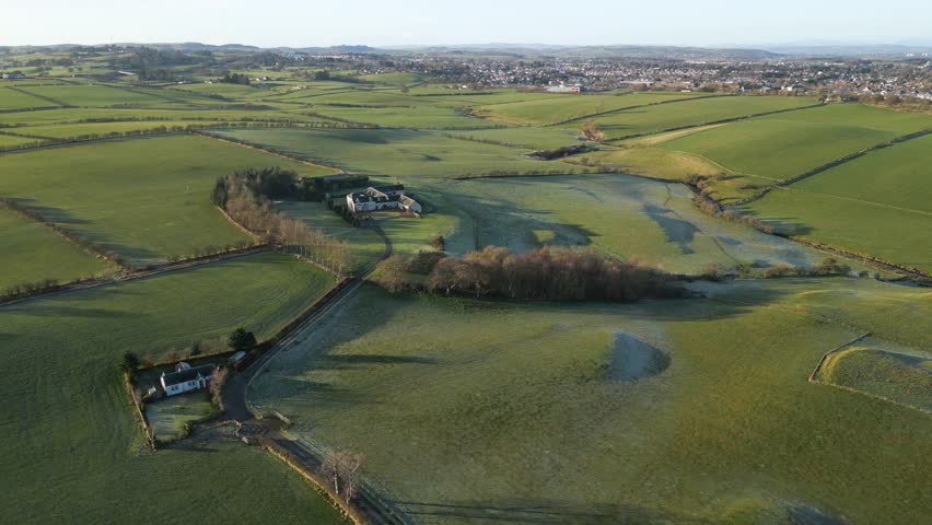 Aerial video of a large green field with separation and a city on the horizon on golden hour.