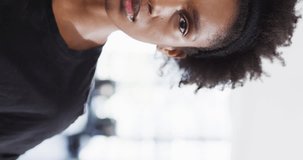 Vertical video half face portrait of smiling african american woman at a gym, with copy space. Fitness and healthy lifestyle.