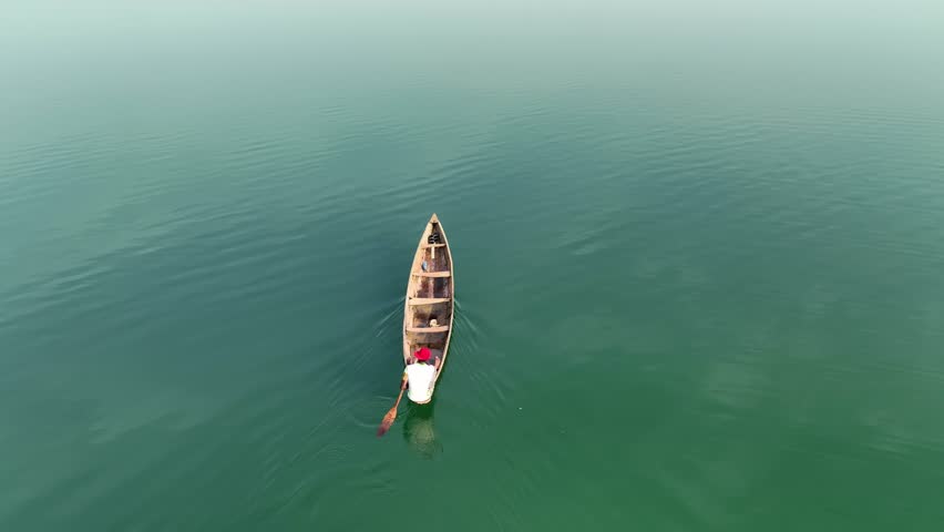 Aerial - Overhead shot of a man rowing his canoe in a lake