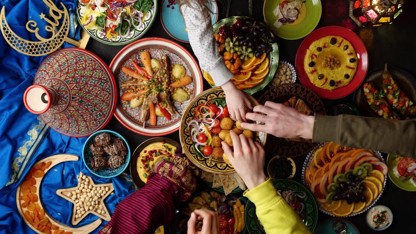 Table prepared for dinner in Ramadan with dates, lamb in tagine, hummus, samosa, falafel, pita bread. Muslim family dinner. Islamic holiday Eid al Fitr | Shutterstock HD Video #1100170649