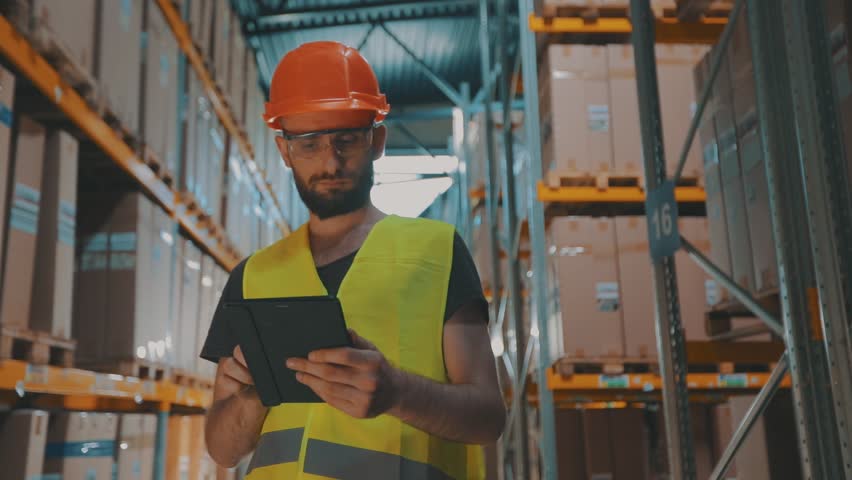 A manager with a tablet in a warehouse checks the goods. Warehouse manager of a large factory. Royalty-Free Stock Footage #1100172601