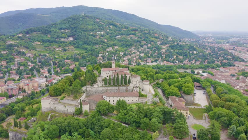 Inscription on video. Brescia, Italy. Castello di Brescia. Flight over the city in cloudy weather. Glitch effect text, Aerial View, Point of interest