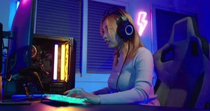 Game Over. Asian gamer playing online video game she losing and sad on computer PC colorful neon LED lights, young woman in gaming headphones feeling disappointed about lost game, E-Sport concept